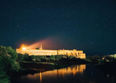 Панорама освітленого Меджибізького замку з Південного Бугу вночі