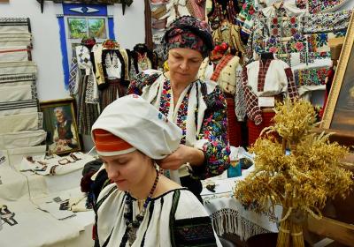 Пожилая женщина одевает на молодую женщину национальный головной убор